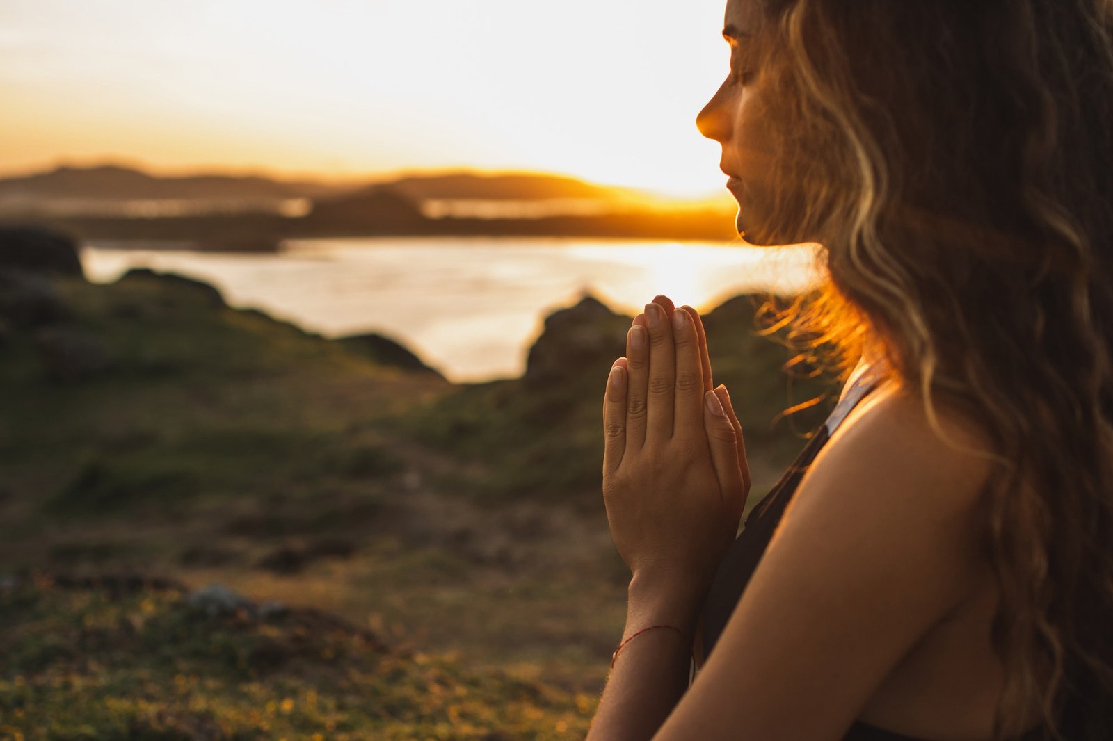 Woman praying alone at sunrise. Nature background. Spiritual and emotional concept. Sensitivity